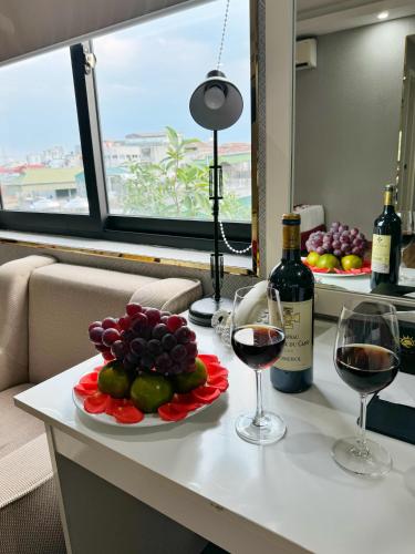 a table with two glasses of wine and a plate of fruit at Sunrise Hanoi Hotel in Hanoi