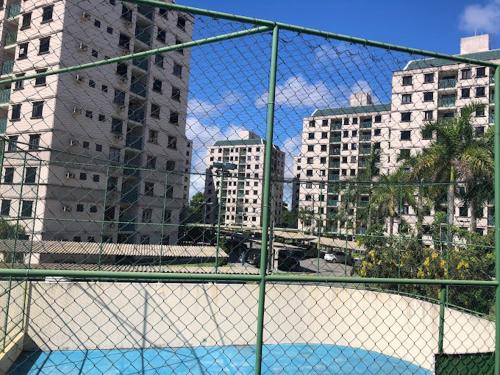 a tennis court behind a fence with tall buildings at Apartamento Farolândia, Aracaju-SE in Atalaia Velha