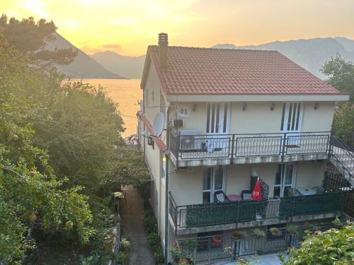 a white house with a balcony and a body of water at Studio on the coast, with a view of the sunrise,free we-fi in Kotor