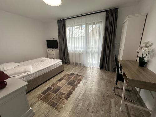 ein Schlafzimmer mit Bett, Schreibtisch und Fenster in der Unterkunft The View Apartment 3 Bușteni in Buşteni