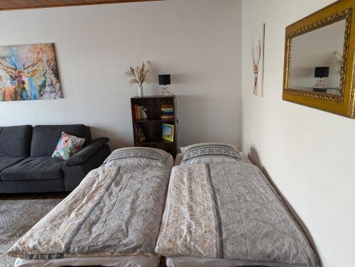 Dos camas en una habitación con un sofá y un espejo. en Ferienwohnung Hennessy, en Marienfels