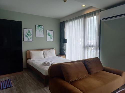 a bedroom with a bed and a couch and a window at The Deck Patong 7Fl Mountain View 1 in Patong Beach