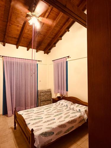 a bedroom with a bed with purple curtains and a ceiling at House in Maroni in Pervolia