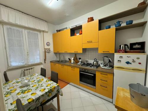 a kitchen with yellow cabinets and a table and a refrigerator at 5 Terre Express Holiday House - Migliarina in Isola