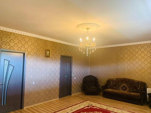 a room with a chandelier and a couch and a chair at Uplistsikhe guest "Paluma" in Kʼvakhvreli