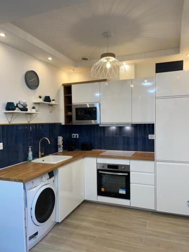 une cuisine avec des armoires blanches et une laveuse et une sécheuse dans l'établissement La cour secrète, à Deauville