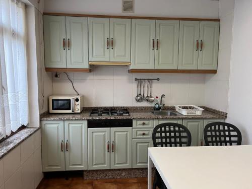 a kitchen with green cabinets and a stove top oven at Hostal Barco da Vella in Merejo