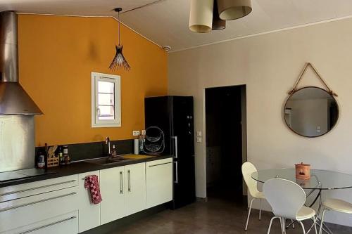 une cuisine avec une table en verre et une salle à manger dans l'établissement Villa 250 m plage 6 personnes La Villanat, à Sérignan