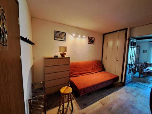 - une chambre avec un canapé orange et une commode dans l'établissement Appartement standard avec balcon, parking et ascenseur à Albiez-Montrond - FR-1-618-9, à Albiez-Montrond