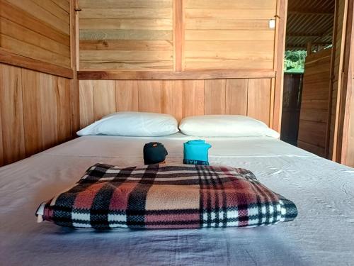 a bed with a blanket and two cups on it at Lodge El Amargal - Reserva Natural, Ecoturismo & Surf in Nuquí