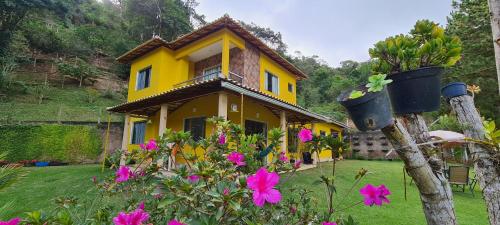 a yellow house with pink flowers in front of it at Casa Amarela da Uruçu in Aracê