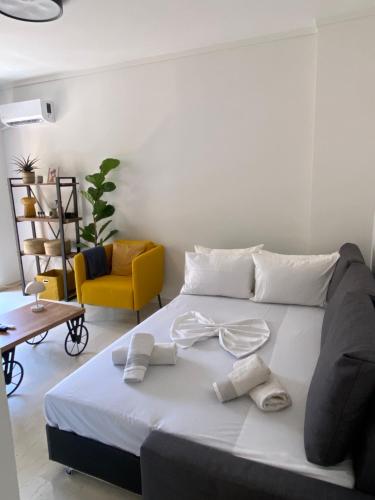 a bedroom with a bed with white sheets and a yellow chair at Blue Cozy Nest in Rhodes Town