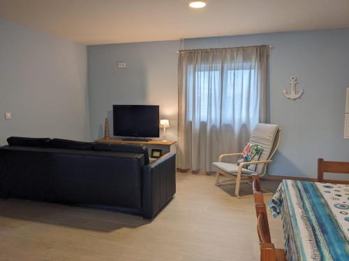a bedroom with a couch and a tv and a chair at T2 na Praia da Costa Nova - Yellow Door in Costa Nova