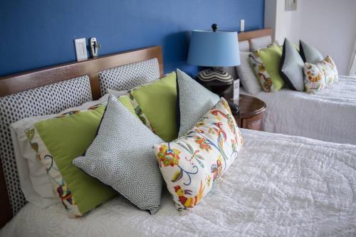a bed with green and white pillows on it at Casa Colina in Isla Navidad