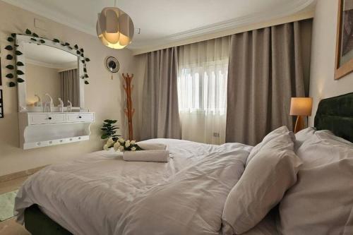 a bedroom with a large white bed and a mirror at Heaven with wide view garden in Madinaty