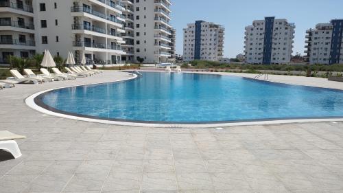 a large swimming pool with lounge chairs and buildings at Nice Flat in Caesar in Iskele