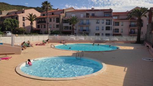 un groupe de personnes dans deux piscines dans une cour dans l'établissement Résidence Port d'Avall - Piscine Parking Clim - 200 m plage - 4 pers - 2 chambres, à Collioure