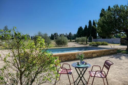 une terrasse avec 3 chaises, une table et une piscine dans l'établissement Sous le mûrier - Mas Provençal au coeur des vignes, à Travaillan