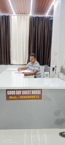 a man sitting at a desk with a sign on it at Hotel O Good Day Guest House in Alandi