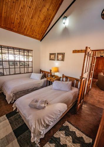two beds in a room with wooden ceilings at Rietpoort Cottage in Parys