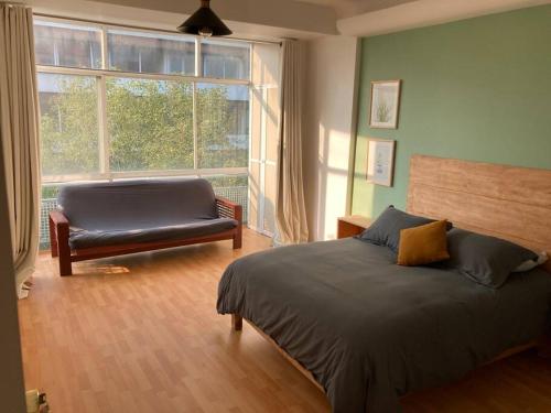 a bedroom with a bed and a couch and a window at Distrito Spencer 2 BR apartment in Polanco in Mexico City