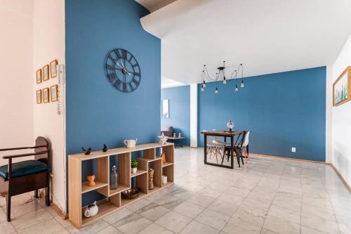 a room with a blue wall with a table and a clock at Distrito Spencer 2 BR apartment in Polanco in Mexico City