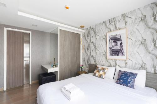 a bedroom with a white bed and a stone wall at Dazzle Sukhumvit 7 by LeFoyer in Bangkok