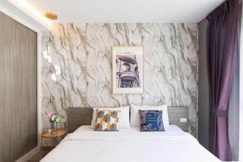 a bedroom with a bed and a wall with a painting at Dazzle Sukhumvit 7 by LeFoyer in Bangkok