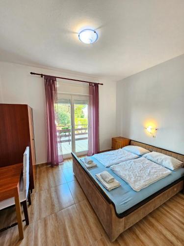a bedroom with a bed and a table and a window at Apartment Milada in Banjol