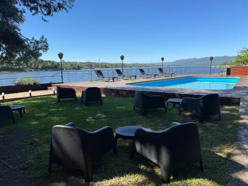 a group of chairs sitting in the grass near a swimming pool at Ciervo de Oro in Villa Carlos Paz