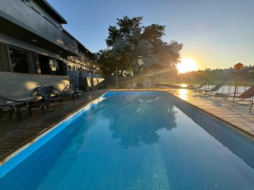a swimming pool with the sun setting behind a building at Ciervo de Oro in Villa Carlos Paz