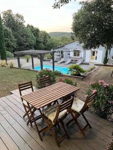 une table et des chaises en bois sur une terrasse en bois dans l'établissement Studio Les Chênes Verts proche Gorges de l'Ardèche, à Labastide-de-Virac