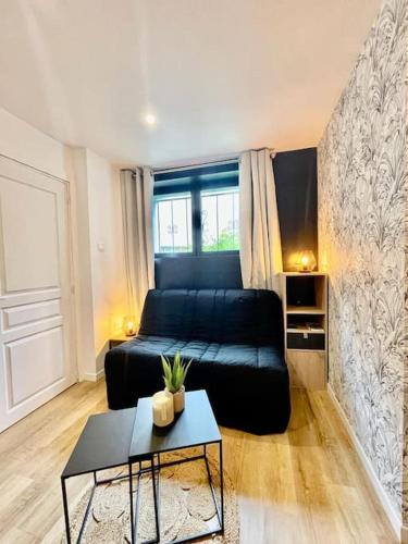 un salon avec un canapé noir et une table dans l'établissement Le studio du Port, à Châteauneuf-sur-Loire