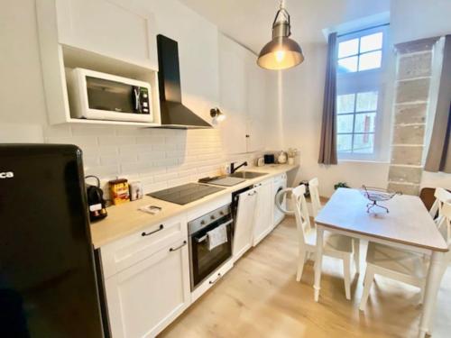 d'une cuisine avec des placards blancs et une table avec une petite sidx. dans l'établissement Le standing du centre historique, à Périgueux