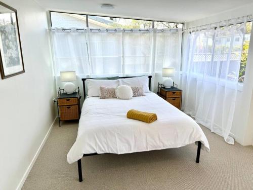 une chambre avec un grand lit blanc avec deux lampes dans l'établissement Yamba Fishing Cottage Haven Wifi boat parking, à Yamba