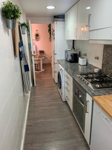 a kitchen with white cabinets and a stove top oven at Apartamento primera línea de playa in Port Saplaya