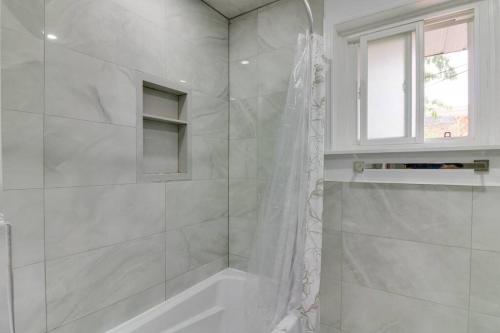 baño blanco con ducha y ventana en Beautiful house near Eglinton GO, en Toronto