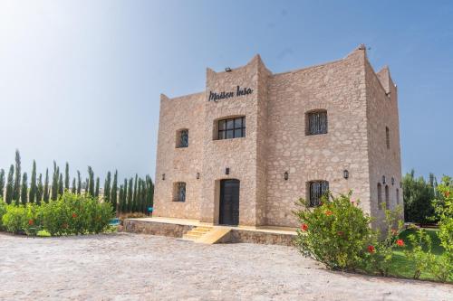 a large brick building in a field with trees at Maison Insa in Essaouira