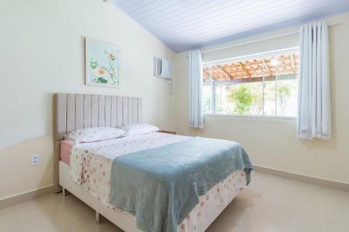 a bedroom with a bed and a window at Bela casa de praia sossegada no Centro de Búzios in Búzios