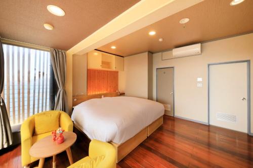 a bedroom with a bed and a table and chairs at Ocean View Hiromi SPA Hotel温泉と絶景の宿 in Shimoda