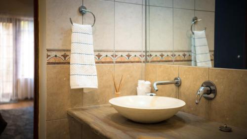 a bathroom with a bowl sink on a counter at Botanica Guest House in George