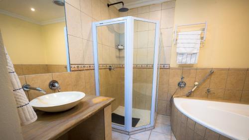 a bathroom with a sink and a shower and a tub at Botanica Guest House in George