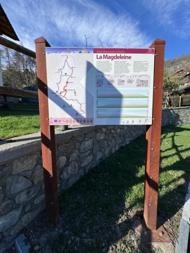 a sign in the grass next to a stone wall at ComeCasa La Magdeleine 2 Bedrooms Apartment in La Magdeleine
