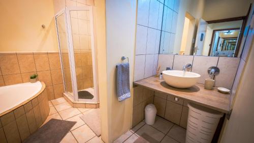 a bathroom with a sink and a shower and a tub at Botanica Guest House in George