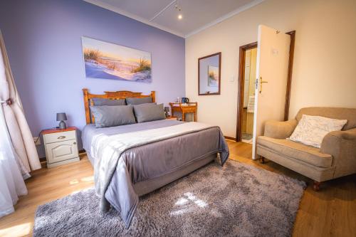 a bedroom with a bed and a couch and a chair at Botanica Guest House in George