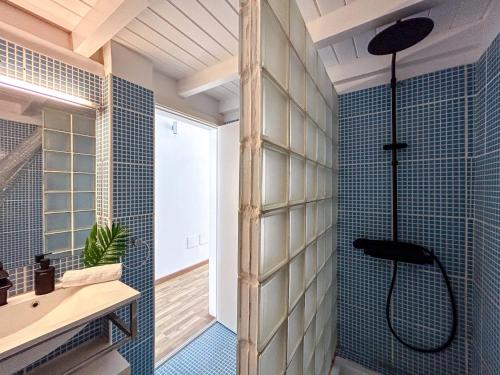 Un baño con ducha con paredes de azulejos azules. en Un hogar lejos de tu hogar, en Sal Rei