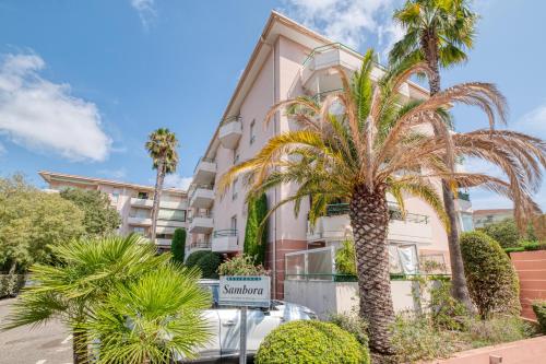 un bâtiment avec des palmiers devant dans l'établissement Appartement Le Sambora - Happy Rentals, à Fréjus