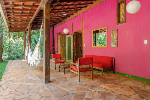 a pink house with red chairs and a table at Casa Quereres - autenticidade e afeto in Brumadinho
