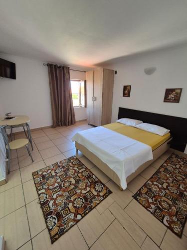 a bedroom with a bed and a table and rugs at Vila Khalo in Mangalia