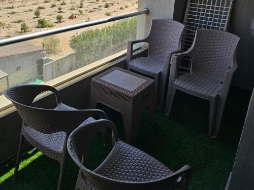three chairs and a table on a balcony at شاليه جراند هيلز الساحل الشمالي in Dawwār ‘Abd Allāh